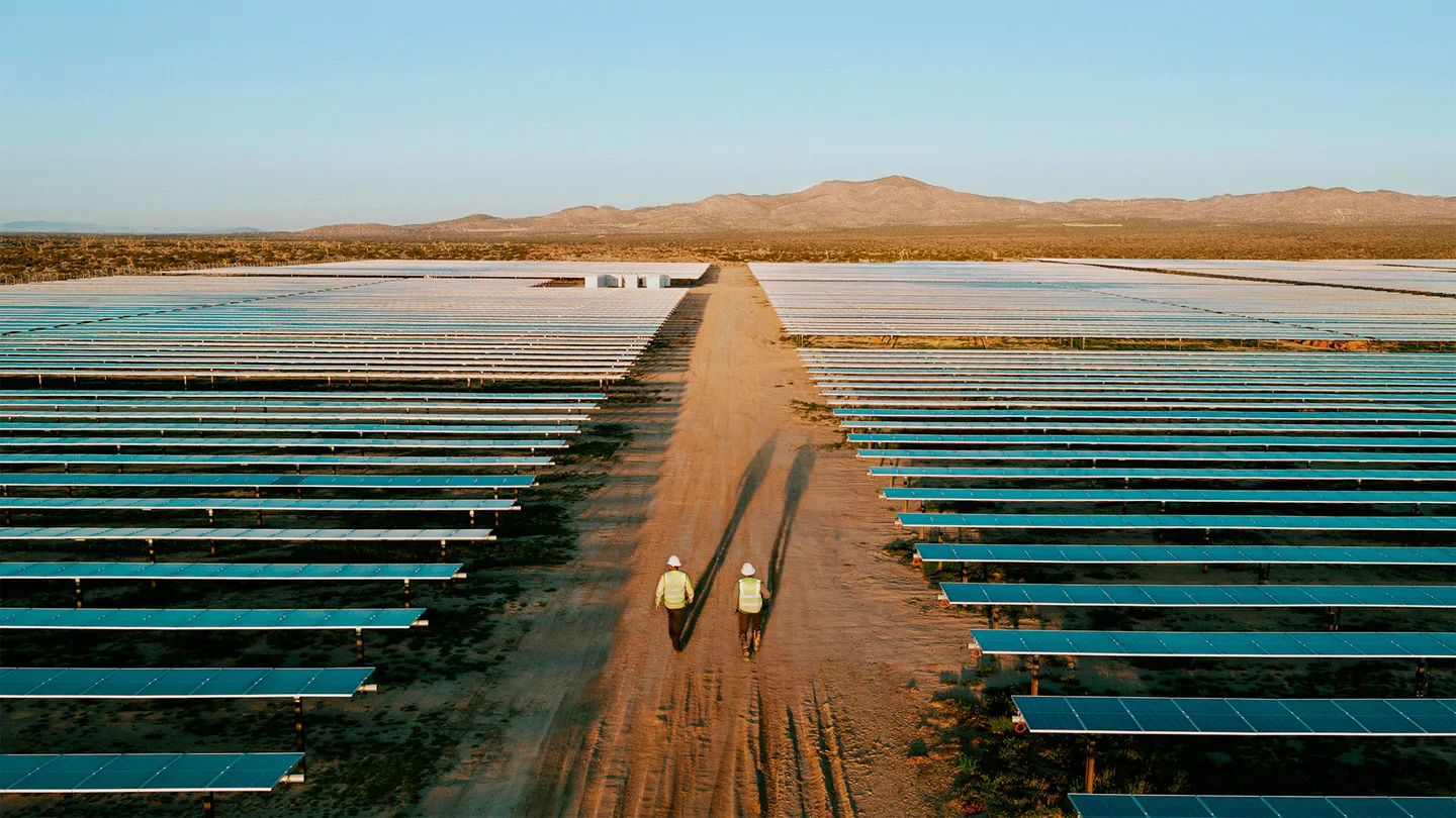 Two workers walking through the Baldy Mesa solar and storage project in Adelanto, California