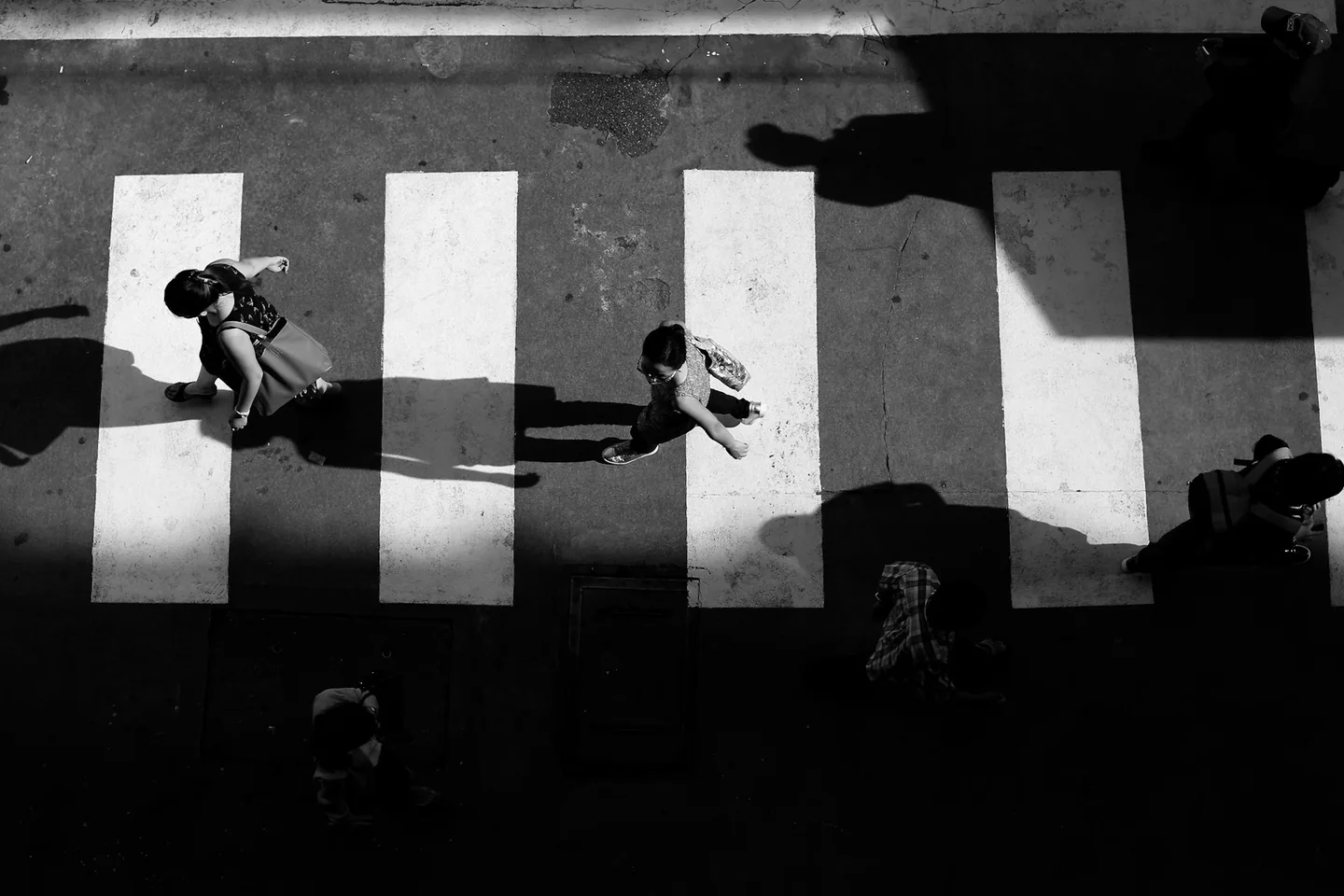 Pedestrians and shadows crossing a striped street