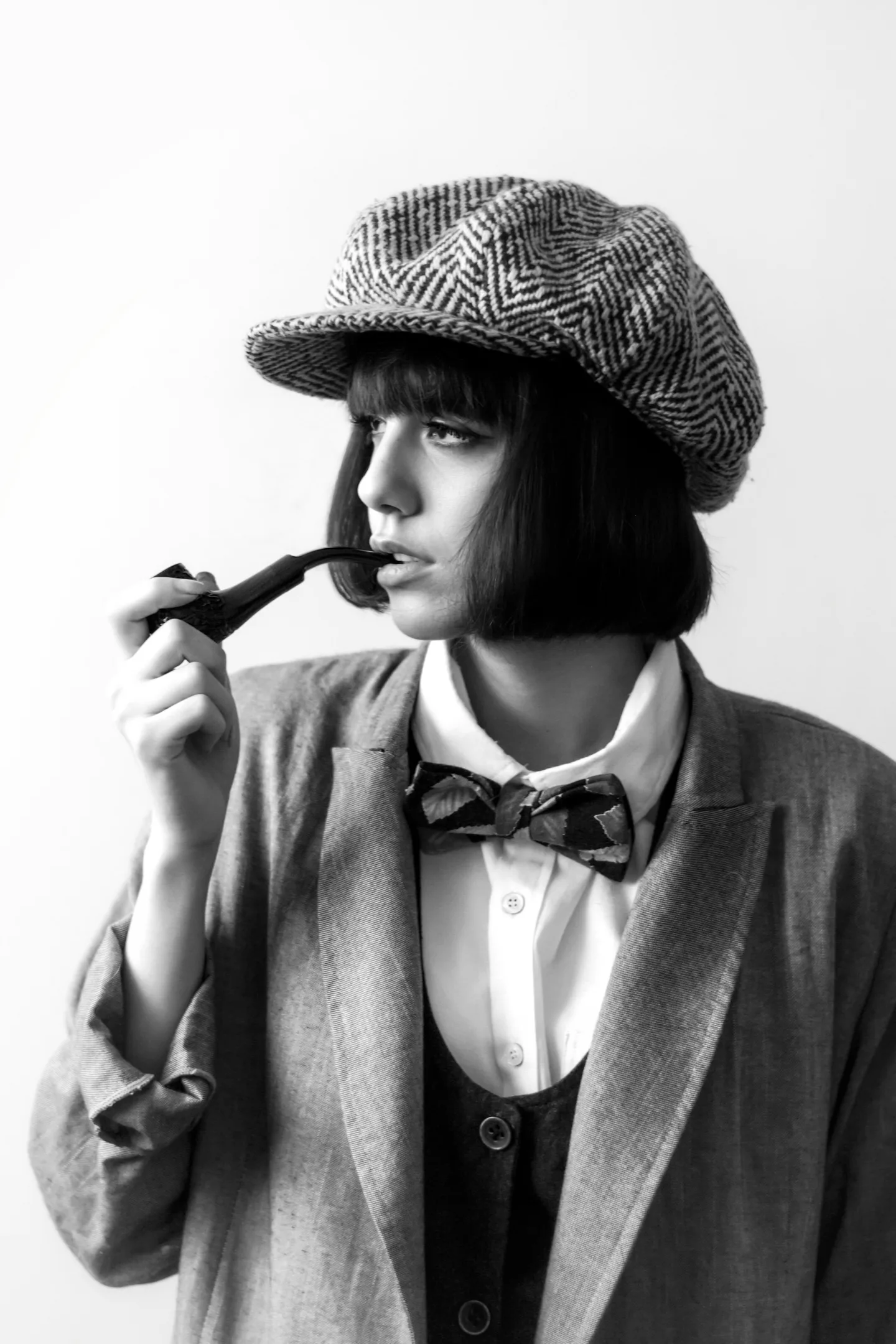 Portrait of a woman wearing a patterned cap and holding a pipe